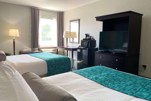 a hotel room with two beds and a flat screen tv at Travelodge by Wyndham Miramichi New Brunswick in Miramichi