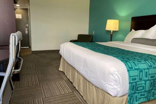a hotel room with a large bed and a chair at Travelodge by Wyndham Miramichi New Brunswick in Miramichi