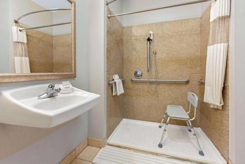 uma casa de banho com um lavatório e um chuveiro com uma cadeira. em La Quinta by Wyndham Bridge City em Bridge City