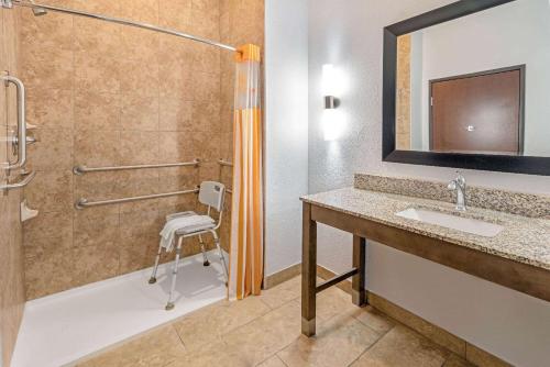 a bathroom with a shower and a sink and a chair at La Quinta by Wyndham Guthrie in Guthrie