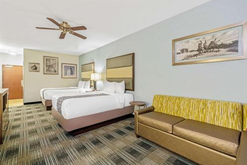 a hotel room with two beds and a couch at La Quinta by Wyndham Guthrie in Guthrie