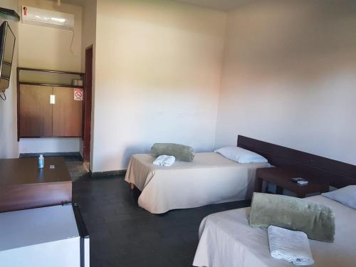 a hotel room with two beds and a desk at Marinas Pousada in Pasto da Mata