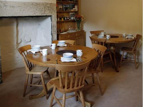 a dining room with wooden tables and chairs and a fireplace at The Reading Rooms in Haydon Bridge