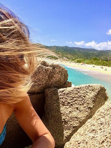 a woman sitting on a rock overlooking the beach at Elena's Maison in Solanas