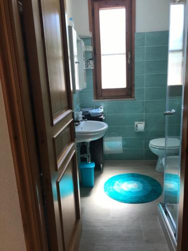 baño con lavabo, aseo y alfombra azul en Elena's Maison, en Solanas