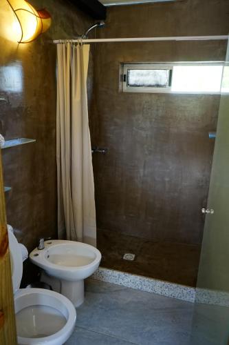 a bathroom with a shower and a toilet and a sink at Altos de la Serena Apart Hotel in La Paloma