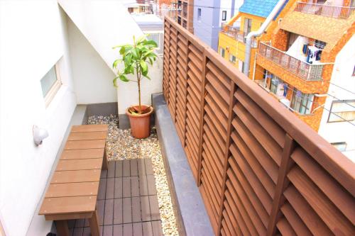 a balcony with a wooden bench and a plant at K's House Tokyo Oasis - Asakusa Downtown in Tokyo