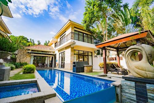 a house with a swimming pool in front of a house at Grand Metropark Villa Resort Sanya Yalong Bay in Sanya