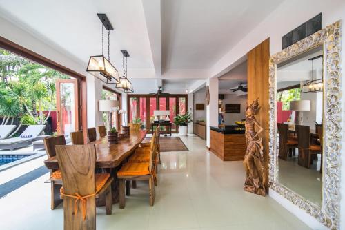 a dining room with a wooden table and chairs and a mirror at CASA MIMBA - Seaview Private Pool Villa Padangbai in Padangbai
