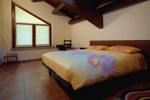 Agriturismo Altana Del Motto Rosso في Gattico: غرفة نوم مع سرير في غرفة مع نافذة