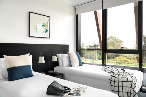 two beds in a room with two windows at Punthill Ivanhoe in Melbourne