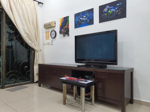 a living room with a tv and a table with a controller at UTHM Parit Raja Homestay in Parit Raja