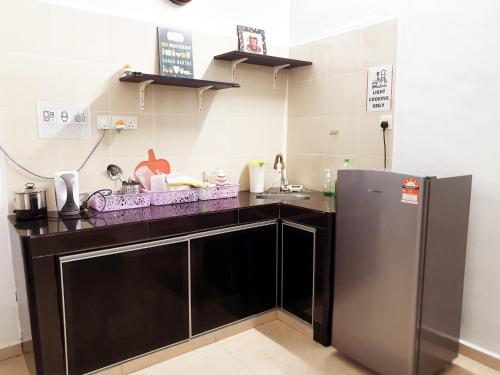 uma cozinha com um balcão preto e um frigorífico em UTHM Parit Raja Homestay em Parit Raja