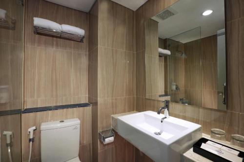 ein Badezimmer mit Waschbecken, Toilette und Spiegel in der Unterkunft Grand Cordela Hotel Bandung in Bandung