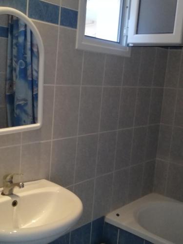a bathroom with a sink and a mirror and a tub at Anestis Studios in Agios Georgios