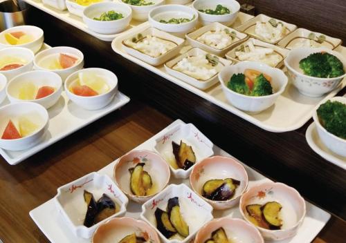 a table with several trays of different types of food at Hotel Green Selec in Sendai