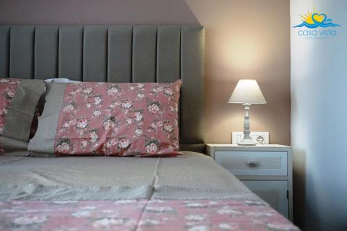 un letto con cuscino rosa e un comodino con lampada di Casa Vista Fall a Karpathos