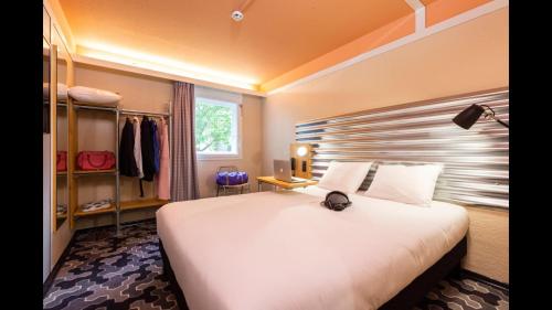 a bedroom with a large white bed and a closet at Ibis Styles Bobigny Centre Préfecture in Bobigny