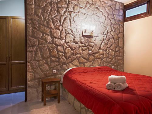 a bedroom with a red bed and a stone wall at 4 Epohes in Elati Trikalon