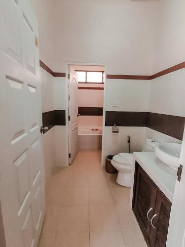 a bathroom with two sinks and a toilet and a window at Chaithalay Khanom Resort in Ban Phang Phrao