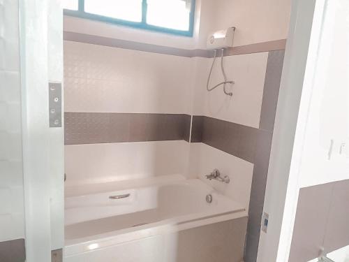 a white bathroom with a tub and a window at Chaithalay Khanom Resort in Ban Phang Phrao