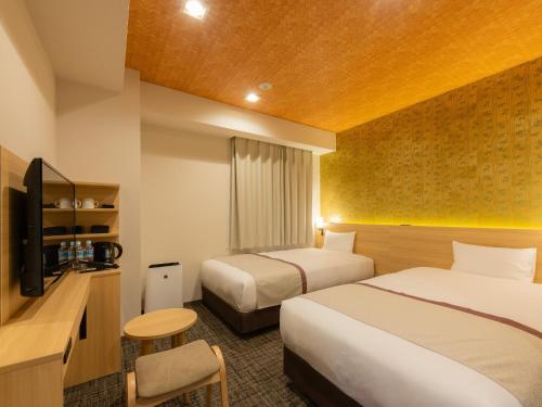 Cette chambre comprend deux lits et une télévision. dans l'établissement Tosei Hotel Cocone Asakusa Kuramae, à Tokyo