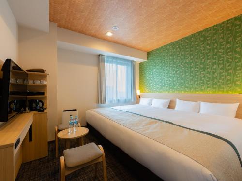 Cette chambre comprend un grand lit et une chaise. dans l'établissement Tosei Hotel Cocone Asakusa Kuramae, à Tokyo