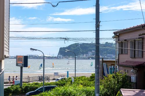 a beach with people in the water and buildings and street lights at KOSHIGOE seaside inn in Kamakura