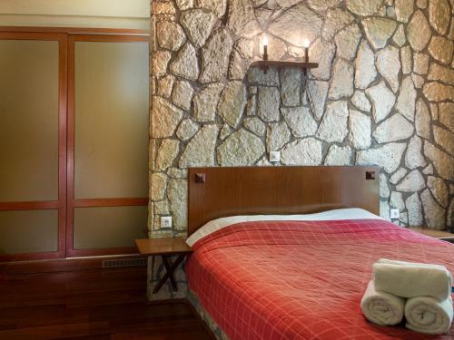 a bedroom with a bed and a stone wall at 4 Epohes in Elati Trikalon