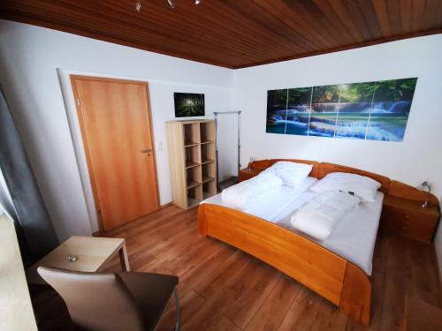 1 dormitorio con cama de madera y almohadas blancas en Ferienappartement -Hof Baum, en Hunswinkel