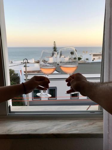 two people holding wine glasses in front of a window at Sea Light Seaview Vista Mar Apartment - Luz, Lagos in Luz