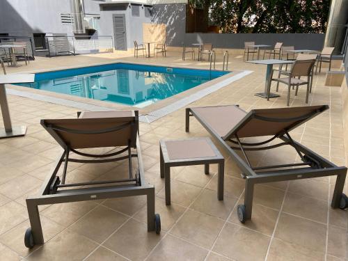 2 sillas y una piscina con mesas y sillas en Hotel Pedro I De Aragon 4 Estrellas SUPERIOR, en Huesca