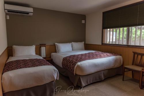 京都市にあるHotel Sou Kyoto Gionのベッド2台と窓が備わるホテルルームです。
