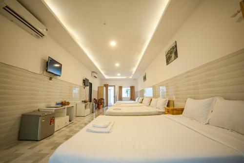 um quarto com três camas e uma tv nele em FaMi Nguyễn Homestay Châu Đốc em Chau Doc