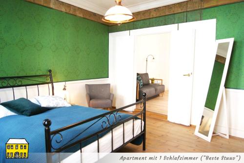 a bedroom with a bed and a green wall at Das Gelbe Haus - Drei besondere Ferienwohnungen in Flensburg