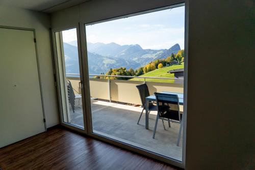 a room with a sliding glass door to a balcony with a table at Ferienwohnungen JHS in Seewis im Prättigau