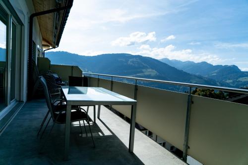 a table and chairs on a balcony with a view of mountains at Ferienwohnungen JHS in Seewis im Prättigau