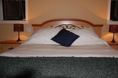 A Vacation Paradise at Quail Ridge B&B في كيلونا: سرير ومخدة زرقاء عليه مصباحين