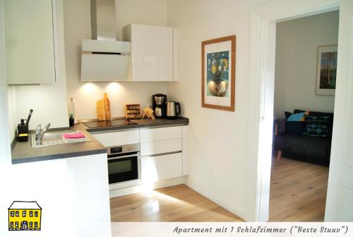 a white kitchen with a sink and a stove at Das Gelbe Haus - Drei besondere Ferienwohnungen in Flensburg