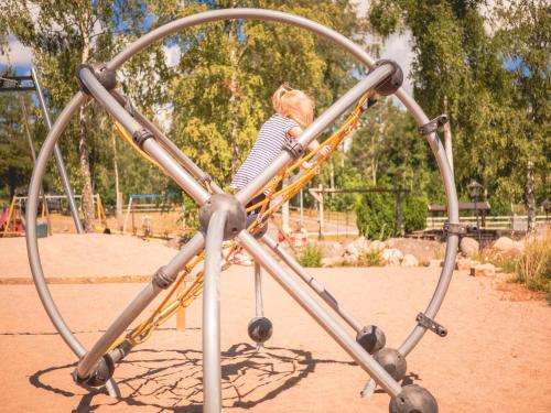 a little girl is riding on a playground at Björkbackens Karaktärshotell in Vimmerby