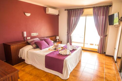 a bedroom with a large bed with purple pillows at Hotel Victoria in Segur de Calafell