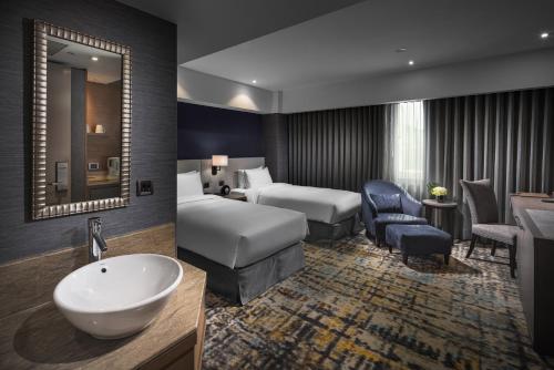 a hotel room with a bathroom with a bed and a sink at Taipei Fullerton Hotel - South in Taipei
