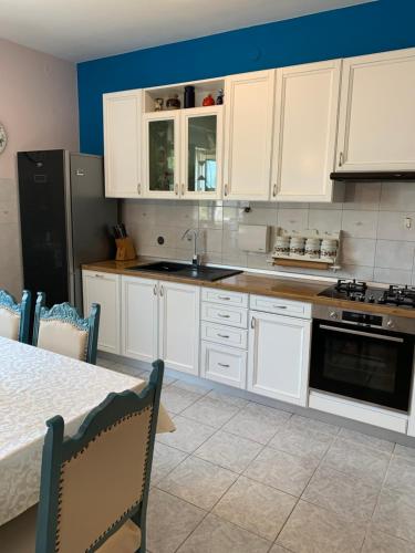 - une cuisine avec des placards blancs, un évier et une table dans l'établissement Holiday Home Endi, à Unešić