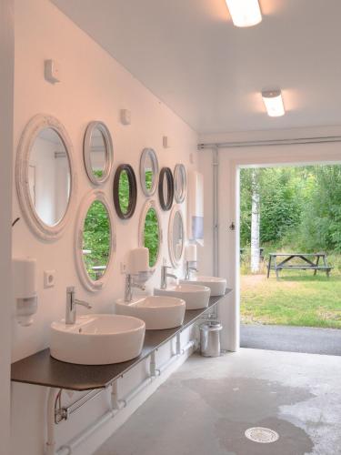 a bathroom with four sinks and mirrors on the wall at Björkbackens Stugby i Vimmerby in Vimmerby