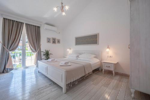 a white bedroom with a bed and a window at Marinero Apartments in Budva