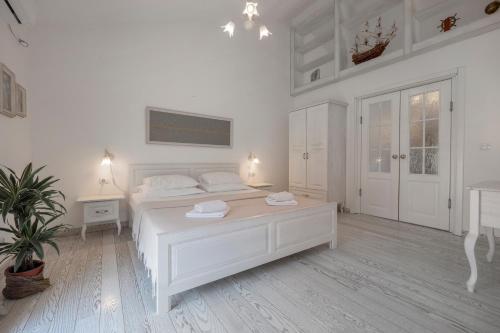 a white bedroom with a white bed and a table at Marinero Apartments in Budva