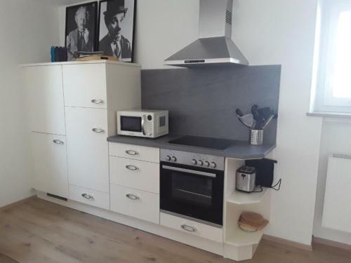 een keuken met een fornuis en een magnetron bij Freundliche Ferienwohnung mit großer Terasse in Aichstetten