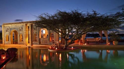 a house with a tree in the middle of the water at The Majlis Resort in Lamu