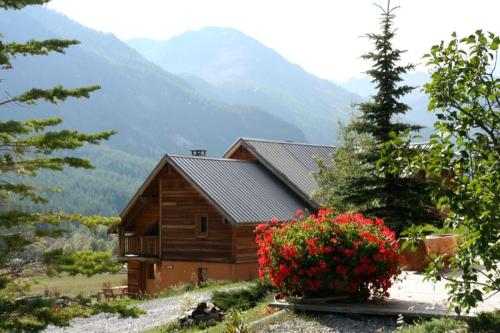 une cabine dans les montagnes avec des fleurs devant elle dans l'établissement L'Aoùro Hameau des Chazals Nevache Hautes Alpes, à Névache