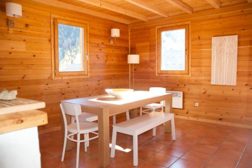 comedor con mesa y sillas en una cabaña de madera en Chalet Le Murè hameau des Chazals Nevache Hautes Alpes en Névache